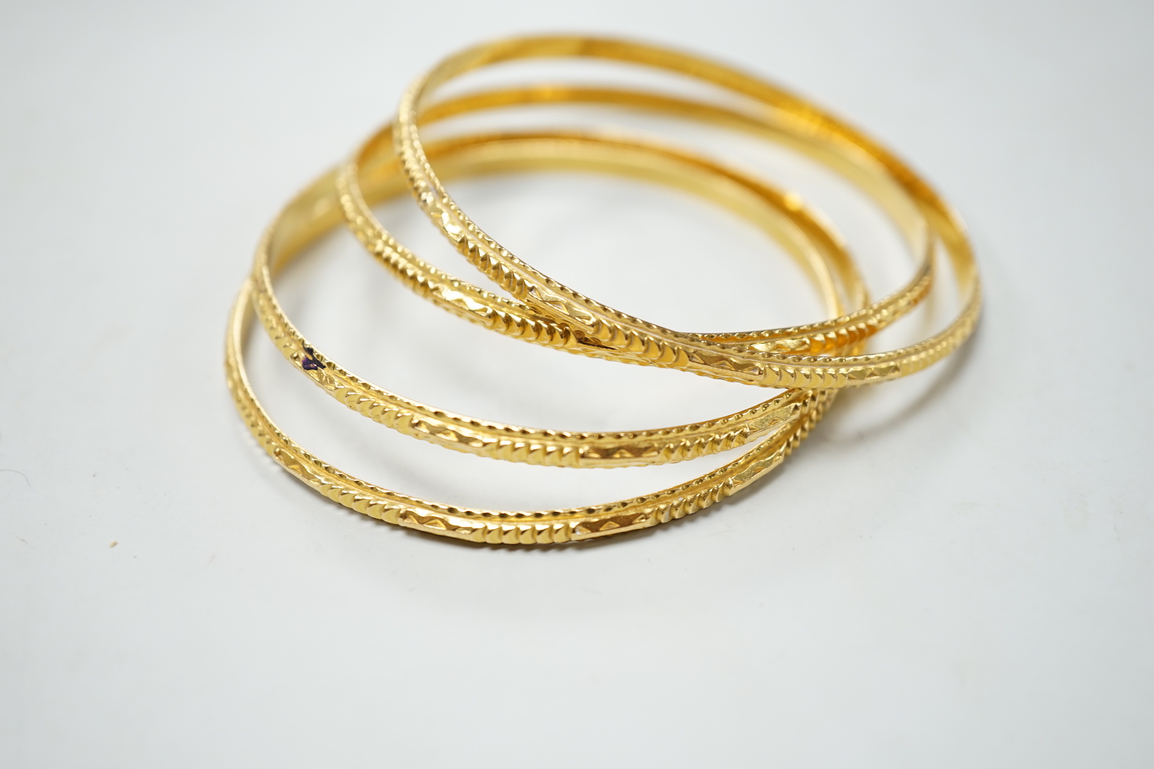 A set of four bright cut yellow metal bangles, 60 grams.